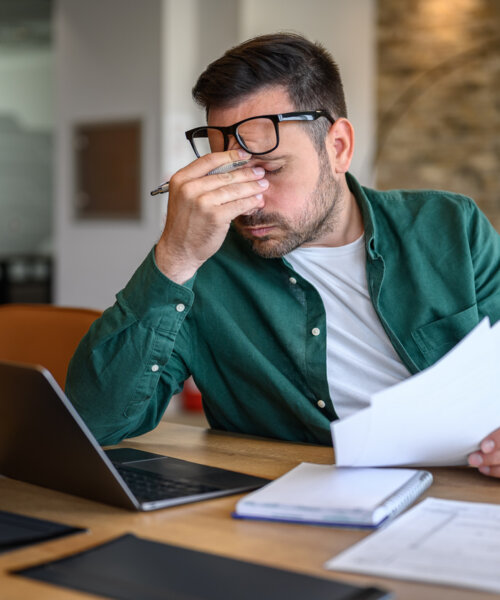 Stressed man looking at bills and his computer