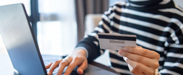 Woman using laptop and credit card at home for online shopping, book at one click